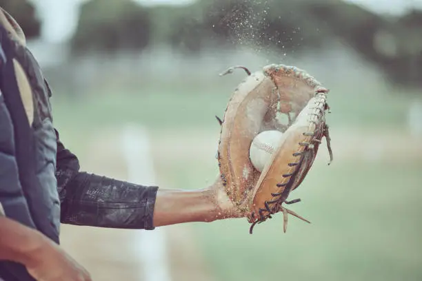 Photo of Baseball, sports and catch with a man athlete catching a ball at a game on a field or grass pitch. Fitness, health and sport with a male baseball player playing a match at a sport venue for exercise