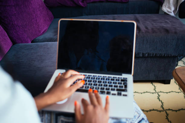 istock Cropped image of dark skinned female using technology at home for booking and banking online, womanâs hands on laptop computer keyboard working online at home interior researching in network 1449632500