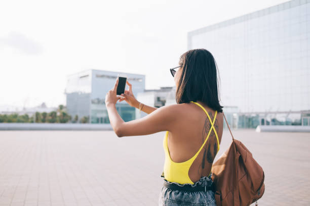 istock Female tourist with backpack taking selfie on city square 1449638433