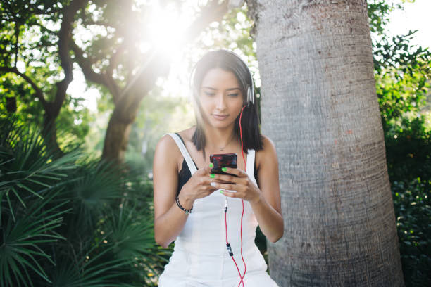 istock Pensive brunette millennial meloman entertaining on free time with music using smartphone and 4G connection,young caucasian woman downloading songs on mobile phone playlist in headphones outdoors 1449638477