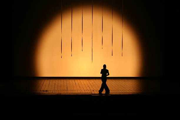 In the stagelight A sole actress on stage silhoetted in the stage light stage actress stock pictures, royalty-free photos & images