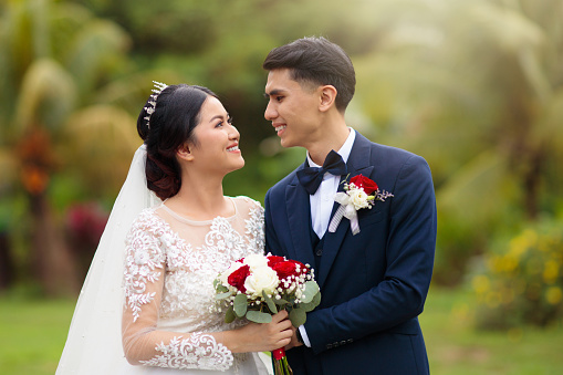 Bride and groom on wedding day. Beautiful young Asian couple. Newly wed man and woman. Just married husband and wife in wedding gown. Love and marriage.