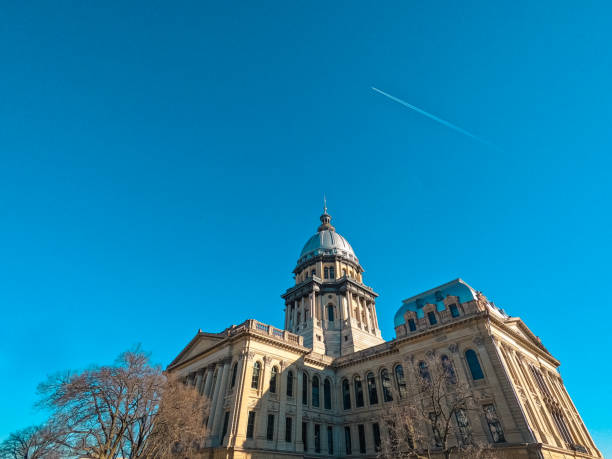 The Illinois State Capitol Building in Springfield, Illinois, USA Distant rear view of the Illinois State Capitol Complex in Springfield, Illinois, USA. Set against a bright blue morning sky. Vapor trails in the background of view. Bare winter trees in the forefront of view. illinois state capitol stock pictures, royalty-free photos & images