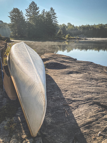 Canoe parked on Canadian Shield rocky outcropping on Big East Lake with misty lake water in the background.