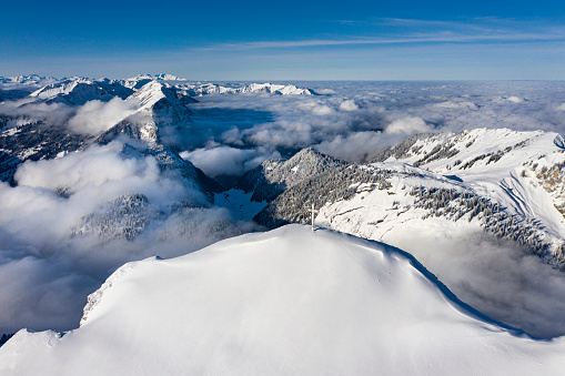 Aerial view of the summit cross on the snowcapped mountain Diedamskopf in Vorarlberg