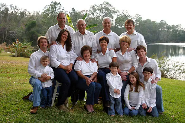 Large family of 14 people in white shirts and denim jeans outside