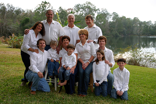 Entire family dressed in white shirts and denim jeans outside, multi-generational family