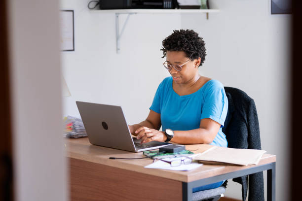 istock Smiling woman working on a laptop in her home office 1449654476