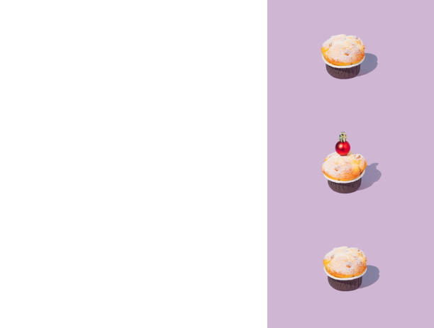Creative pattern made of cupcake decorated with shiny red Christmas bauble. Trendy concept, collage on a purple and white background. Creative art minimal aesthetic. Copy space.