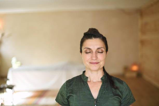 Female therapist looking at camera with eyes closed, feeling the energy