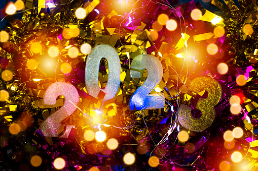 happy new year's 2023 on colorful tinsel and light bokeh
