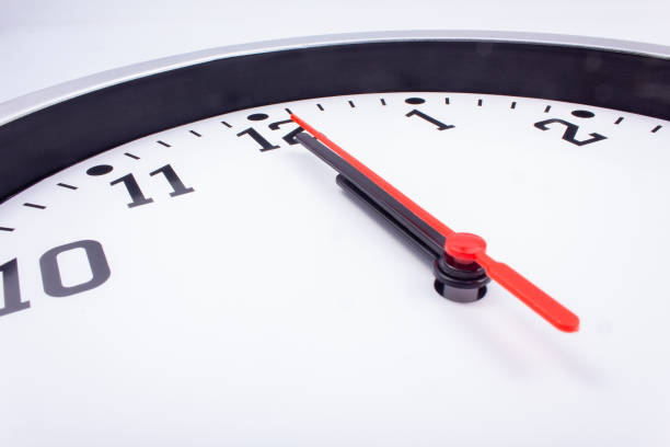 istock Midnight. Black and white office clock with a red pointer on a gray background. 1449659553