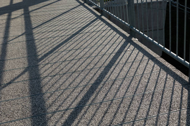 close up view looking down to the long shadows projected on a concrete surface by the sunlight