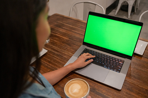 A Women Checking her Computer in a Cafe, Checking a computer in a cafe, Chromakey computer screen in a cafe, Multiracial Women in a Cafe Checking her computer