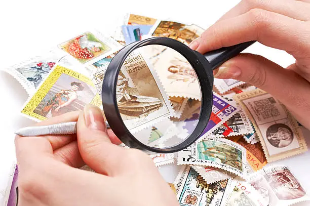 woman looking at an old stamp collection with magnifier