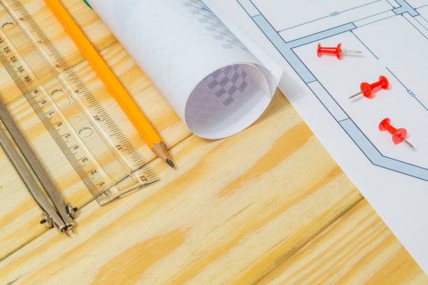 istock Rolled house diagrams and accessories for drawing lying on construction drawing and wooden boards 1449664452