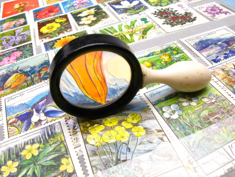 old magnifying magnifier and collection of stamps, close up