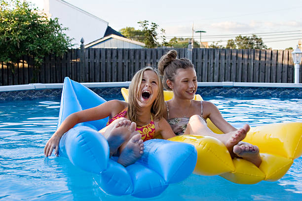 Kids on inflatables in swimming pool stock photo