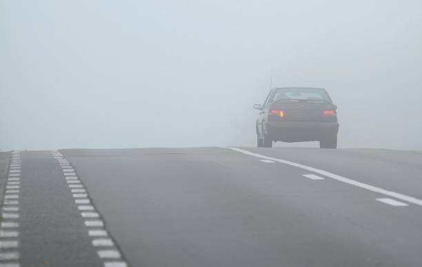 Car disappearing through fog stock photo