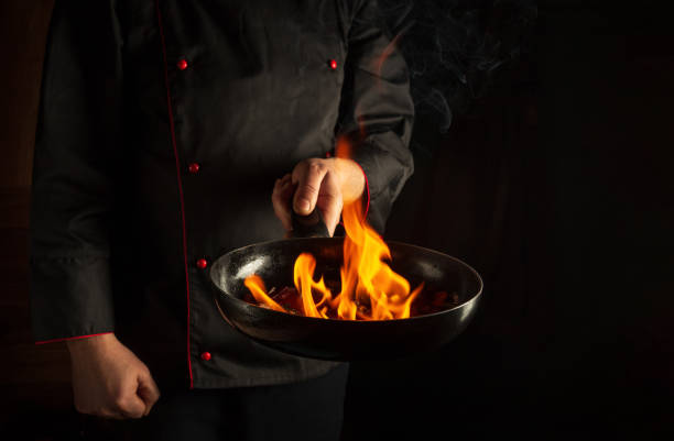 istock Professional chef cooking food in pan with fire flame on black background. Restaurant and hotel service concept. European cuisine. Vegetarian cuisine. 1449675165