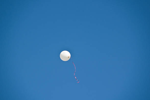 Biała wstążka z czerwony balon w błękitne niebo – zdjęcie