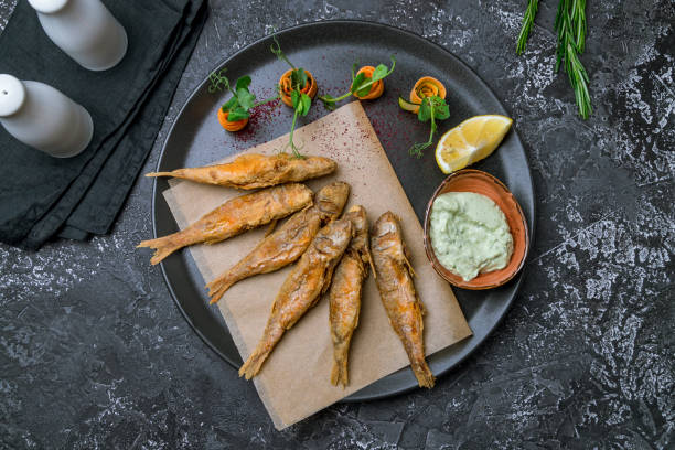 fried surmullet on black plate with sauce top view
