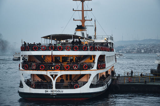 A ferry leaving the Istanbul Karaköy pier on a rainy day, fishing rods on the bridge and the view of Istanbul. November 25, 2018