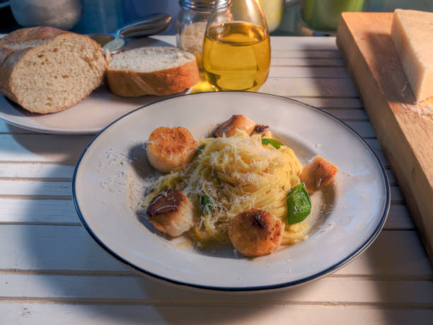 Side view scallops and pasta dish on natural wood surface
