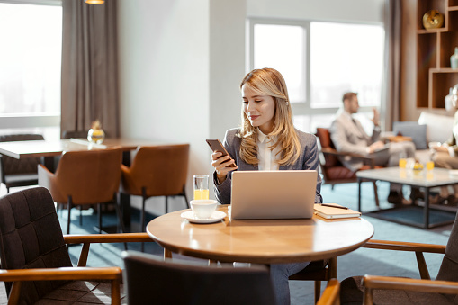 Young businesswoman using smartphone while sitting in business lounge