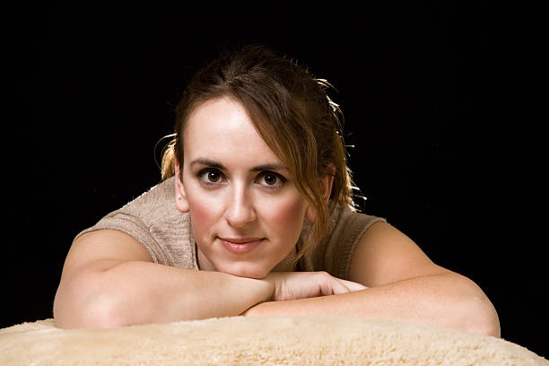 Face of an attractive brunette woman leaning on arms over black