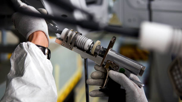 fondo industrial con el proceso de pintar el bastidor del automóvil. escena. vista lateral de cerca de la mano del trabajador con un spray de pintura en la producción de automóviles. - música industrial fotografías e imágenes de stock