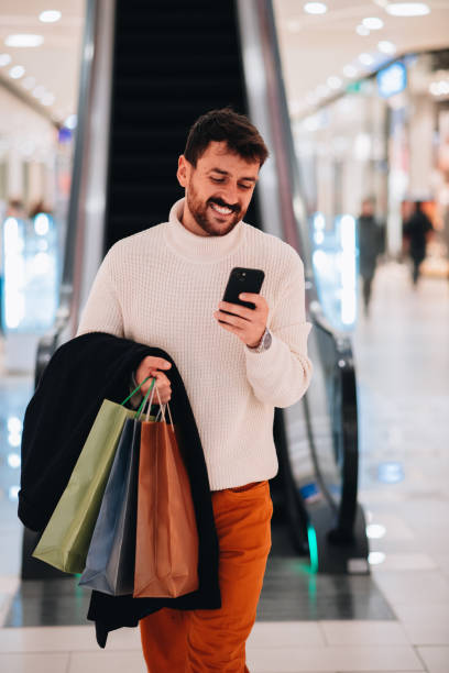 istock Young attractive man texting his girlfriend after a successful shopping spree 1449700263