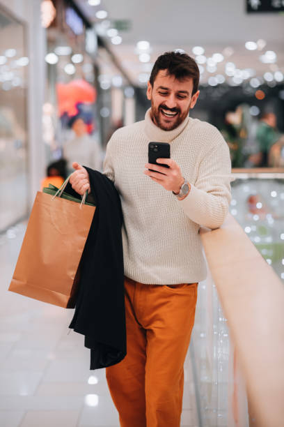 istock Attractive young man using his phone while shopping at the mall 1449704022