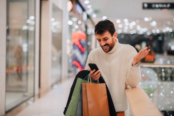 istock Attractive young man using his phone after shopping at the mall 1449704068