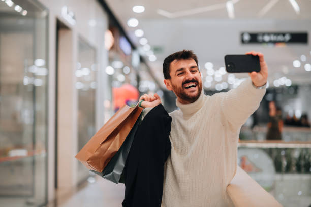istock Attractive young man taking a selfie while shopping at the mall 1449704098