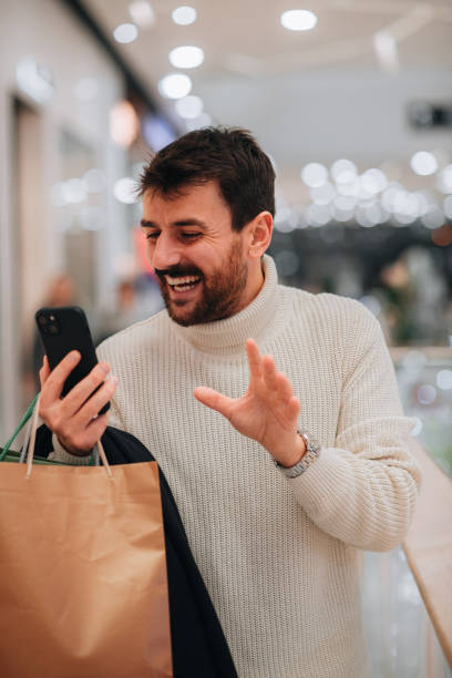 istock Happy man using phone while shopping in a mall 1449704460