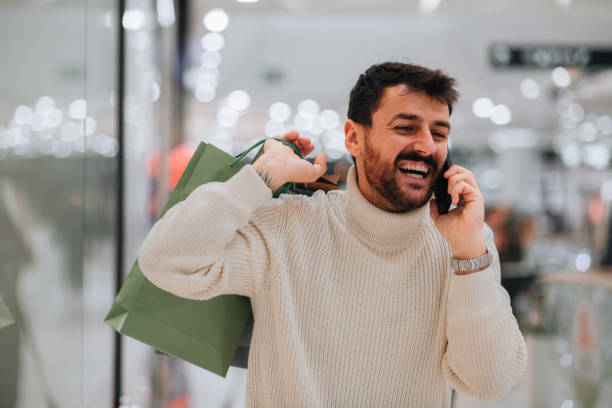 istock Man holding shopping bags while on the phone 1449704525