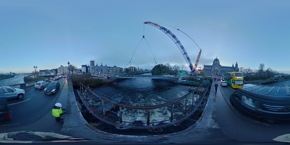 Galway, Ireland - December 12th, 2022 
Brand new pedestrian and cycle bridge over the River Corrib, adjacent to the existing Salmon Weir Bridge captured being welded into position carried precisely by gigantic crane on Monday 12th December. The bridge was constructed on the grounds of the cathedral carpark over past weeks.