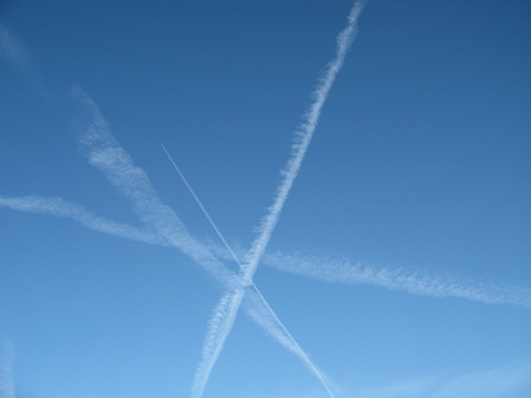 Multitude of crossing jet trails in a bright blue sky