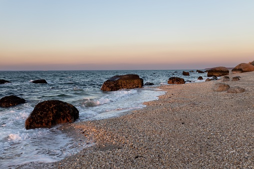 A beautiful view of rocks on a beach with clear sky during sunset