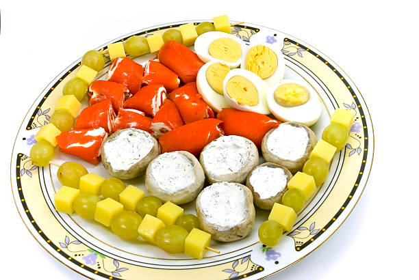 A beautifully arranged cold cuts platter featuring ham, salami, and cheese, garnished with decorative eggs and vegetables, served on a banquet table.