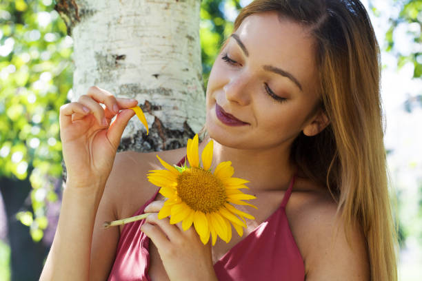 Beautiful young carefree woman wearing white dress and enjoying on sunflower field at summer.
