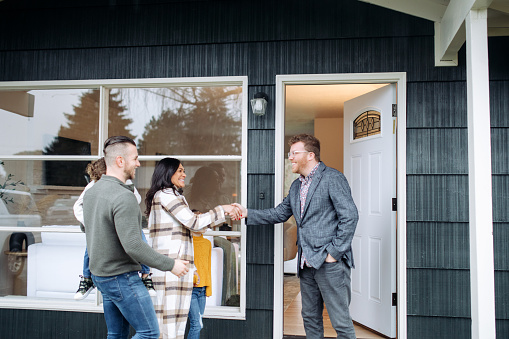A Caucasian Real Estate Agent welcomes a multi-ethnic family to a viewing of a home they are interested in buying.  Shot in Washington state, USA.