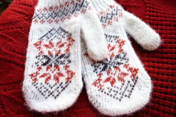 istock Fluffy white knitted mohair mittens with a traditional floral pattern on the back. A pair of mittens fashion accessories. Knitted with red and black threads geometric jacquard pattern. Winter clothes. 1449718124