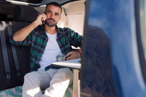 istock man sitting inside his camper van talking on phone 1449718171