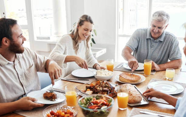 Lunch, family home celebration and grandparents hosting a dinner at kitchen table with smile, food or breakfast. Couple, food and senior people eating meal together with love in their happy house