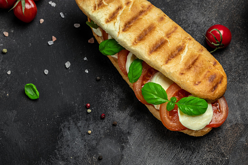 Pressed and toasted panini caprese with tomato, mozzarella and basil, Caprese Panini Sandwich. Delicious breakfast or snack, Clean eating, dieting, vegan food concept. top view.