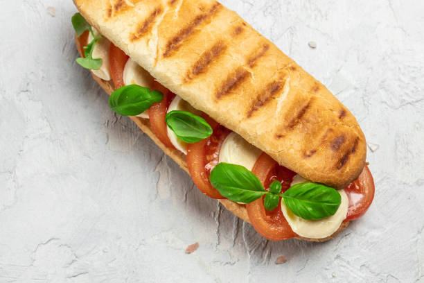 istock Pressed and toasted panini caprese with tomato, mozzarella and basil, Caprese Panini Sandwich. Delicious breakfast or snack, Clean eating, dieting, vegan food concept. top view 1449737584