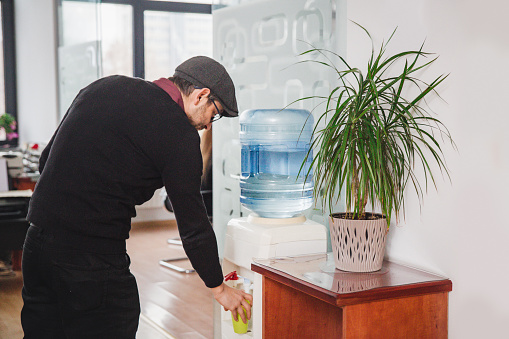 man in the office putting water from water cooler in the office.