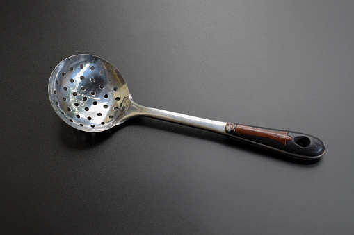 Stainless Steel Round Kitchen Skimmer or Skimmer Spoon Isolated on Black Background, Skimming Ladle